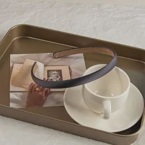 Detail view of the sleek black headband with anti-slip brown velvet lining on a bronze tray