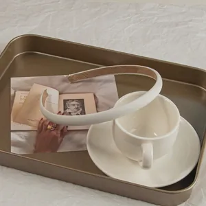 Close-up of cream slim headband with anti-slip suede lining on an elegant coffee cup