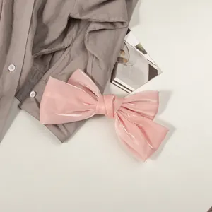 Détail macro d'une grande pince à cheveux nœud en satin rose nacré sur fond neutre