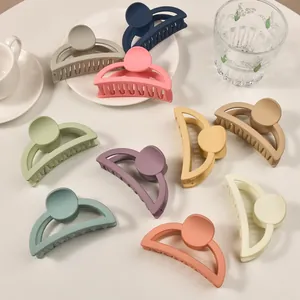 Flat lay of colorful matte semi-circle hair claws in various Morandi shades on a table