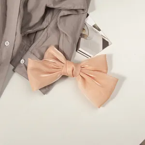 Détail du nœud à cheveux en satin nacré avec texture organza et finition rose pâle