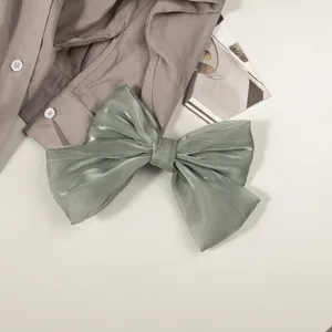 Détail du nœud papillon en satin nacré vert sauge avec des couches de tissu élégantes
