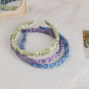 Detail of satin pleated headbands in pastel green, purple and blue with silk texture