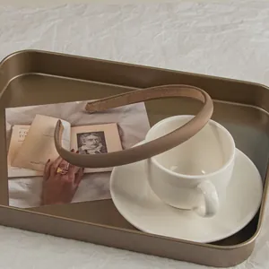Detail of a brown matte fabric headband with non-slip velvet lining in a metal tray
