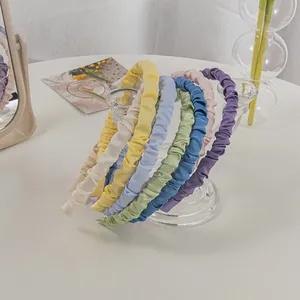 Set of pleated satin headbands in seven pastel colors displayed on a glass rack