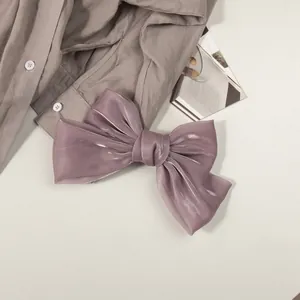 Détail de la pince à cheveux nœud en satin nacré avec une texture de soie brillante