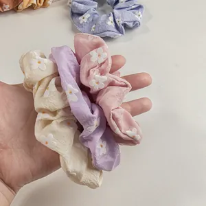 Detailansicht von Blumen-Haargummis in Pastellfarben mit kleinen Gänseblümchen