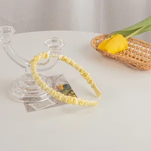 Close-up of yellow pleated satin headband on a glass stand with spring decor
