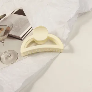 Detail of cream matte hair claw clip with rounded arc design on a minimalist background