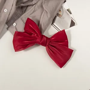 Détail macro du nœud papillon en satin rouge brillant sur fond de tissu gris clair