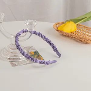 Close-up of purple satin pleated headband with elegant scrunchie texture in a lifestyle setting