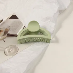 Detailed view of large avocado green matte claw clip on aesthetic magazine background