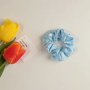Detailaufnahme eines hellblauen Haargummis mit weißem Gänseblümchen-Muster aus Stoff