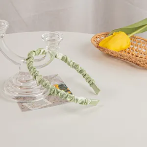 Detail of light green pleated satin headband with elegant texture and glossy fabric finish