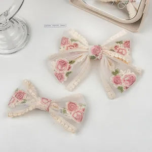 Floral embroidered mesh bow hair clips in apricot with elegant lace trim details
