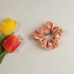 Detail eines orange-rosa Blumen-Scrunchie mit Gänseblümchen-Print und Tulpen-Deko