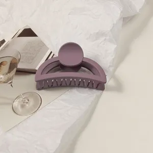 Detailed macro view of a matte purple hair claw clip on a minimalist white background