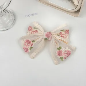 Detail of embroidered rose patterns and lace edges on the tulle bow hair clip