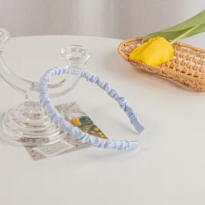 Close-up of light blue pleated satin headband with elegant scrunchie texture and detail