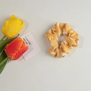 Detailansicht des gelben Blumen-Haargummis mit Gänseblümchen-Print aus Baumwolle