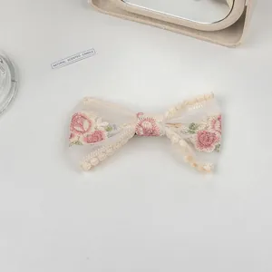 Close-up of white mesh hair clip with pink rose embroidery and delicate lace edges