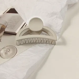 Close-up of matte cream hair claw clip on textured background with French aesthetic