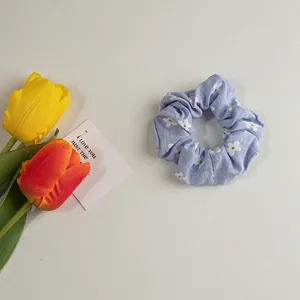 Detailaufnahme von helllila Blumen-Haargummi mit weicher Stoffstruktur und floralen Mustern