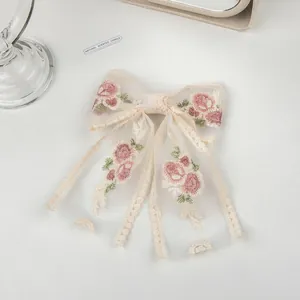 Close-up of mesh lace bow hair clip with delicate pink flower embroidery and scalloped edges