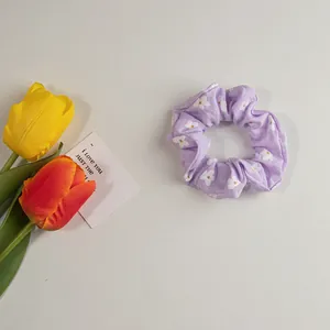 Details eines hellvioletten Haargummis mit Gänseblümchen-Muster und Frühlingsblumen-Deko