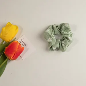 Detail eines hellgrünen Blumen-Haargummis mit weichen Falten und Tulpendekor