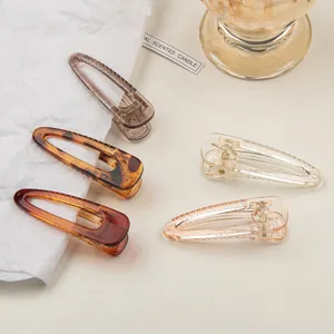 Close-up of five transparent resin hair clips in amber, grey, and pink tones