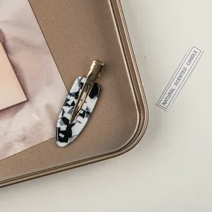 Detailed close-up of marble pattern acetate hair clip on a vintage bronze metal tray