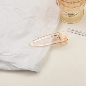 Close-up of a champagne transparent acrylic hair clip with a sleek hollow teardrop design