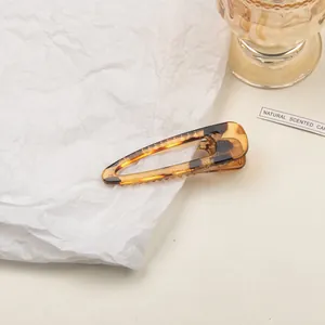 Macro detail of amber tortoise shell triangle hair clip with non-slip teeth texture