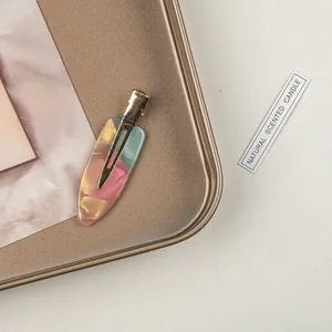 Close-up of pink and green gradient acetate hair clip on a vintage bronze metal tray