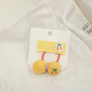 Close-up of yellow bow hair tie with pink cherry embroidery on white display card