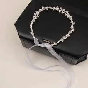 Elegant white pearl headband with long organza ribbons on a minimalist black background