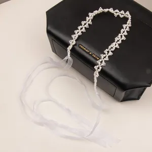 Elegant white pearl mesh headband with sheer organza ribbons on a luxury leather bag