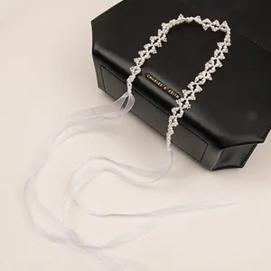 Close-up of woven pearl headband with elegant white mesh ribbons on a black purse