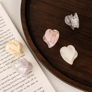 Mini acetate heart hair claws in pastel colors set on a rustic wooden tray decor