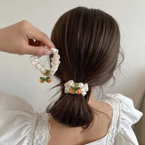 Two-piece set of white satin scrunchies with orange persimmon charms for hair styling