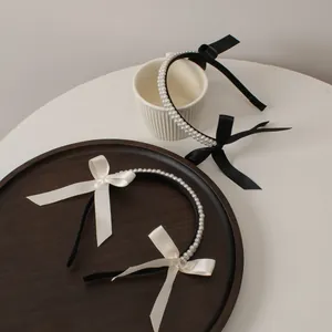 Detail of double-row pearl headbands featuring elegant black and white satin bow accents