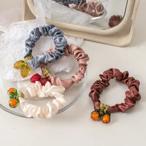 Detailed view of satin scrunchies with cute glass-like fruit pendants in various colors