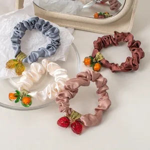 Set of four satin scrunchies with glass fruit pendants in assorted soft pastel colors