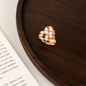 Mini heart acetate hair claw with brown checkerboard pattern on a wooden tray