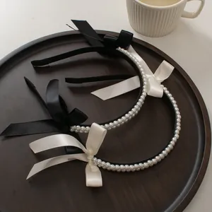 Detail of double-row pearl headbands with satin bows in black and white on a tray