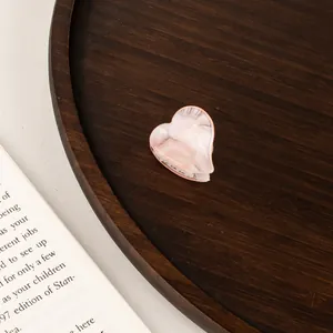 Macro detail of a mini pink heart claw clip with premium marble acetate texture finish