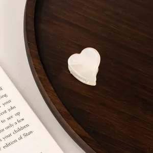 Macro detail of a pearl white heart-shaped acetate hair claw clip on an aesthetic background