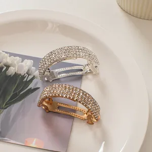 Detailed view of silver and gold curved spring hair clips with sparkling rhinestones