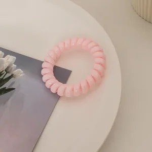 Nahaufnahme eines rosa Spiralgummis in Telefonkabel-Optik auf einem dekorativen Tablett